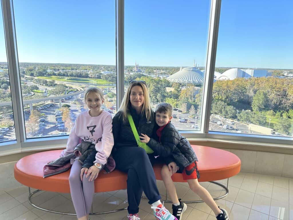 Jennie with her and son and daughter on a bench in front of floor to ceiling windows