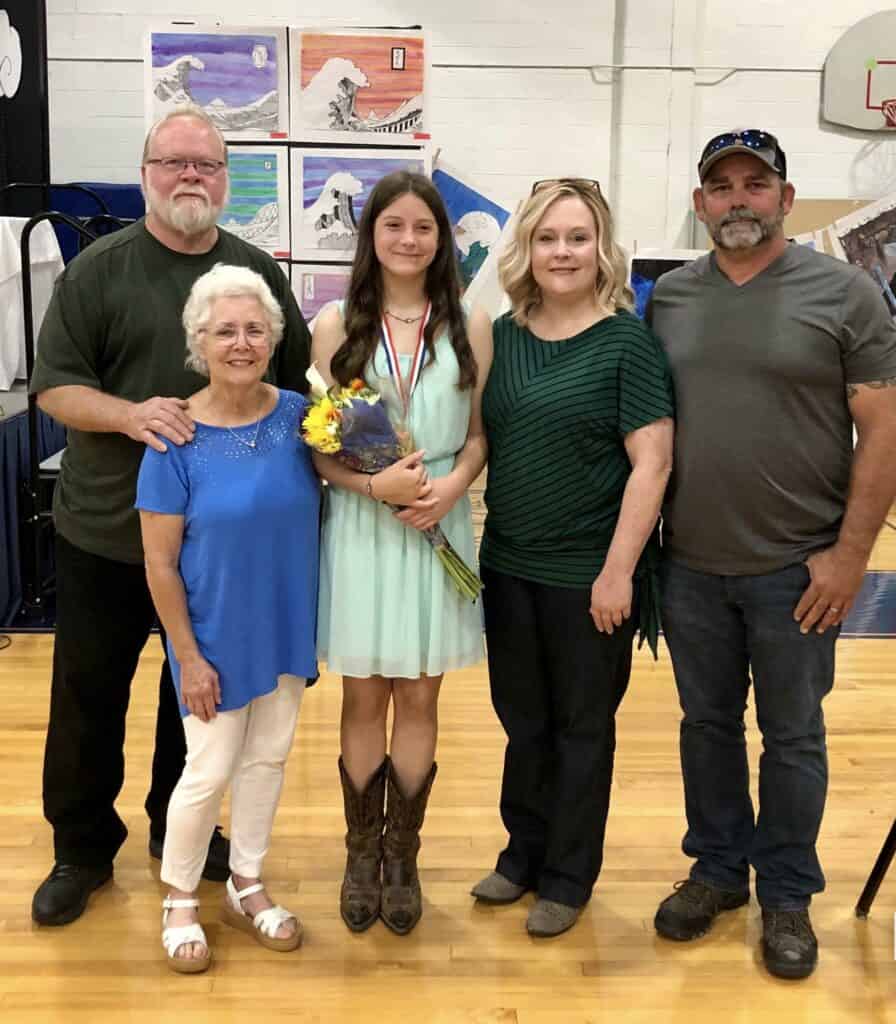 Lisa smiles with family at an event in a school gym