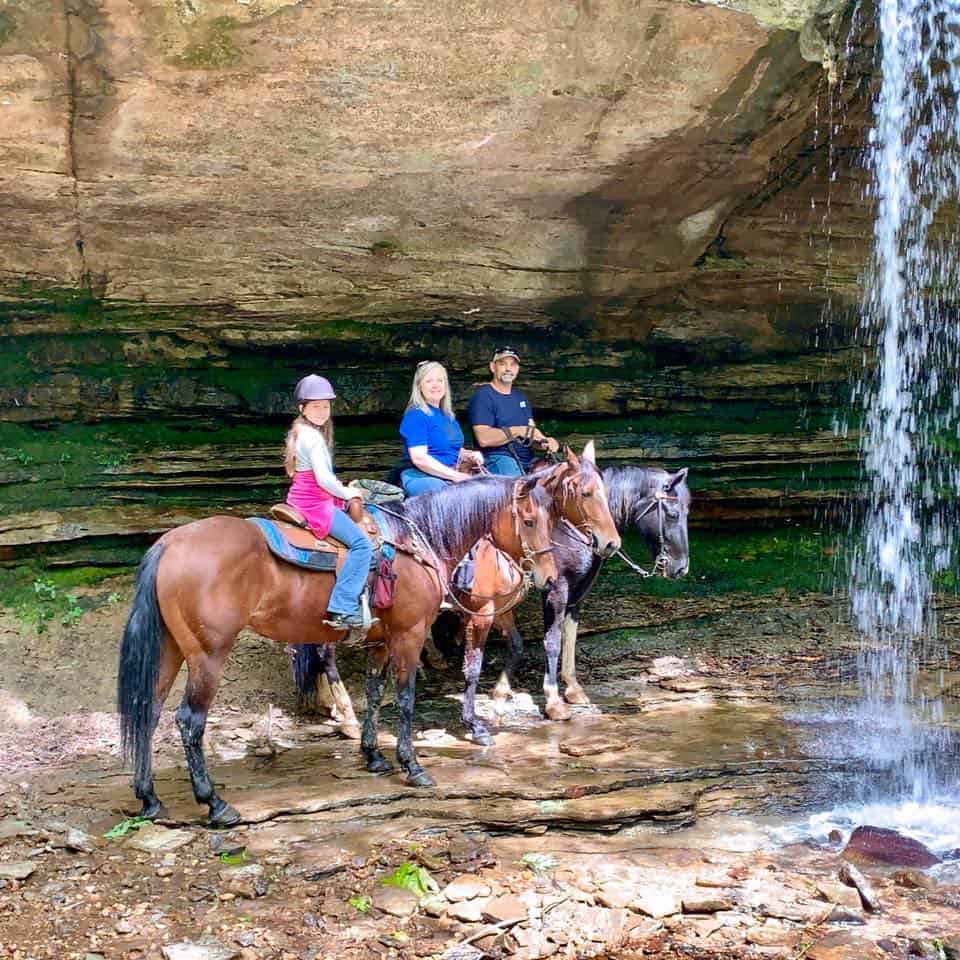 Breast cancer survivor Lisa and family ride horses outside near a waterfall