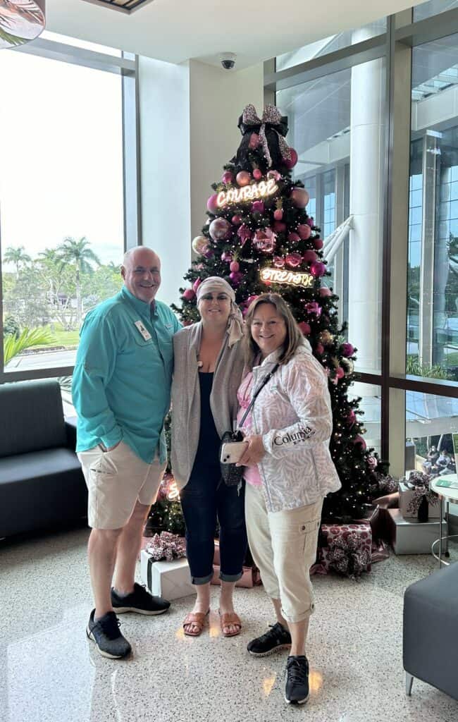 Natalie smiles with family in front of Christmas tree